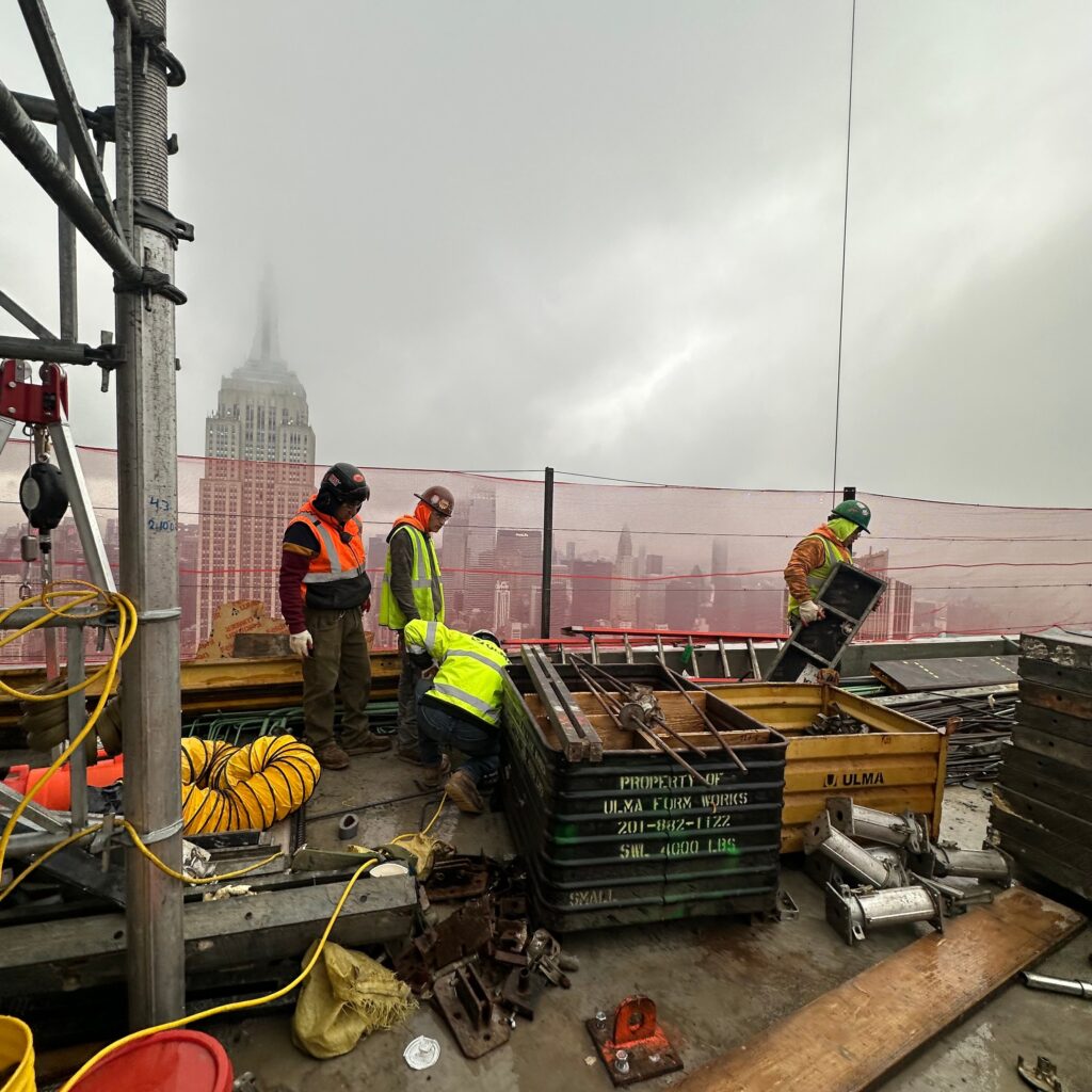Andrew Horan Alba supervising NYC construction and demolition operations with safety gear, modern equipment, and city skyline in the background.