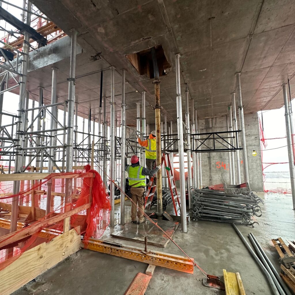 Andrew Horan Alba supervising NYC construction and demolition operations with safety gear, modern equipment, and city skyline in the background.