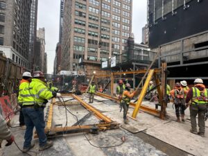 Andrew Horan Alba supervising NYC construction and demolition operations with safety gear, modern equipment, and city skyline in the background.
